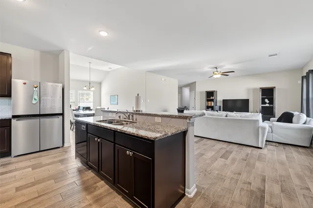 a kitchen with stainless steel appliances granite countertop a table chairs refrigerator and microwave