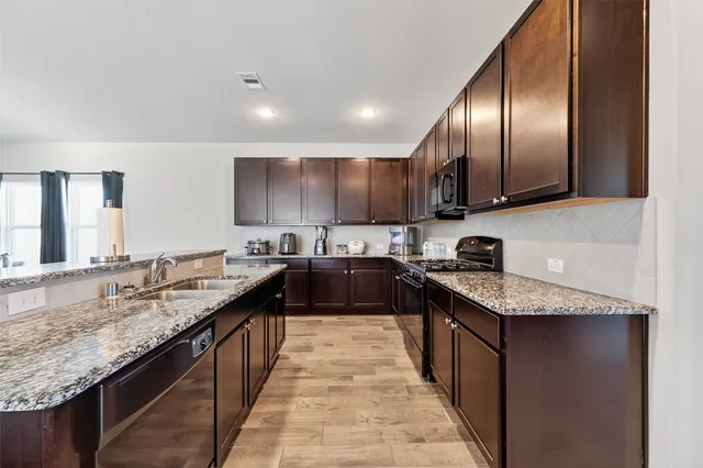 a large kitchen with granite countertop lots of counter space and a sink