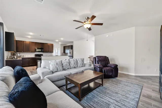 a living room with furniture and a view of kitchen