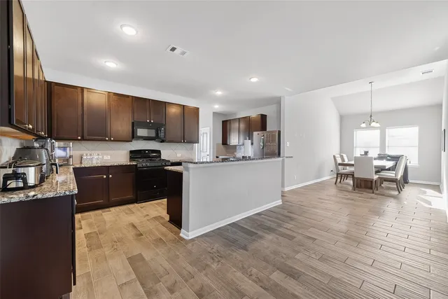 a kitchen with granite countertop wooden cabinets a counter top space and stainless steel appliances