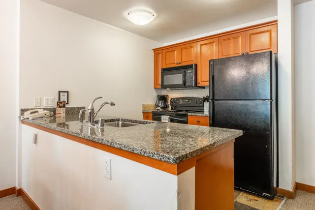 a kitchen with stainless steel appliances granite countertop a sink a refrigerator and a granite counter tops