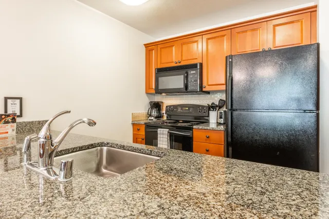 a kitchen with stainless steel appliances kitchen island a refrigerator sink and wooden cabinets