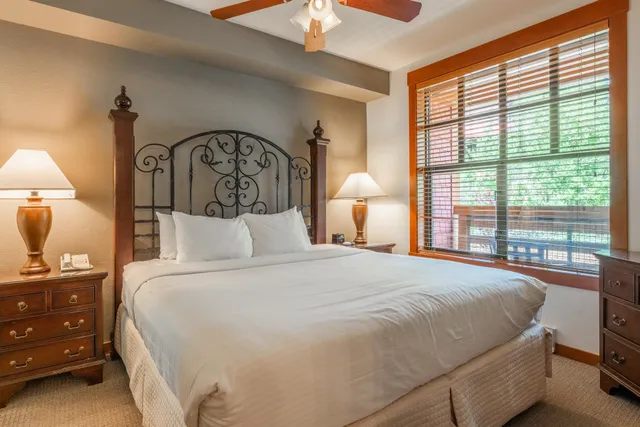 a bedroom with a bed a lamp and a large window