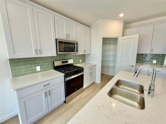 a kitchen with granite countertop a sink stove and microwave