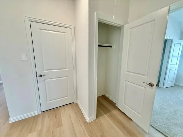 an empty room with wooden floor and entrance