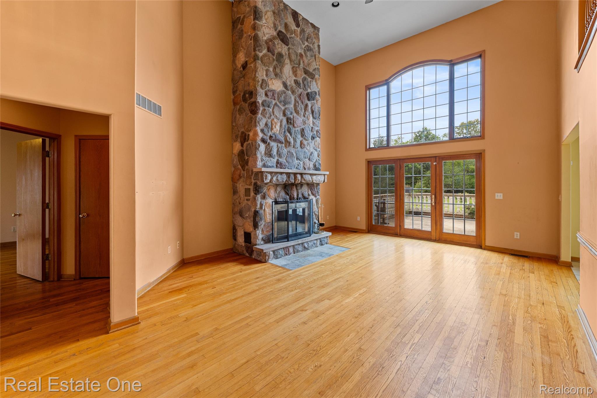 17268 Beech Daly Road Romulus, MI 48174 - Photo 27 of 60 Natural wood-finish flooring, two-story stone fireplace, vaulted ceiling, large arched window, and double french doors