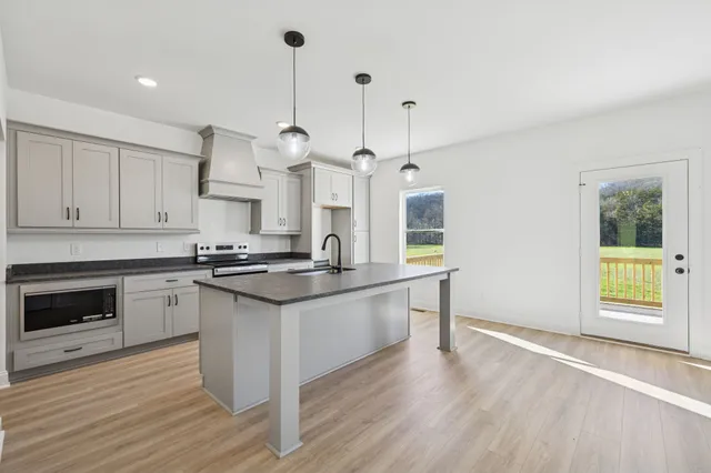a kitchen with stainless steel appliances granite countertop a stove a sink and a wooden floors