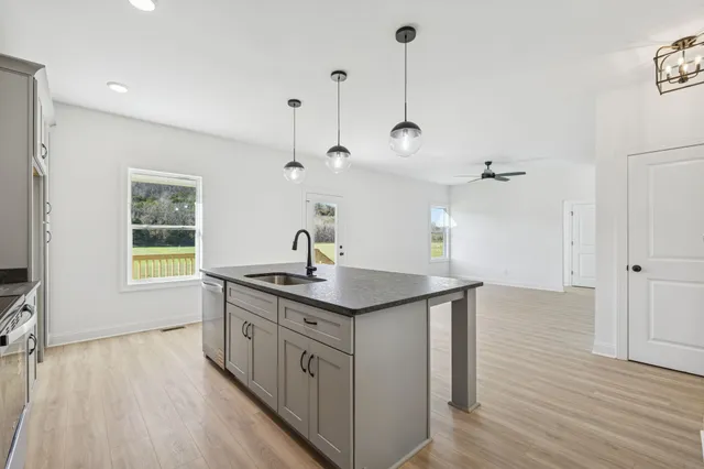 a kitchen with stainless steel appliances granite countertop a sink a window and wooden floor