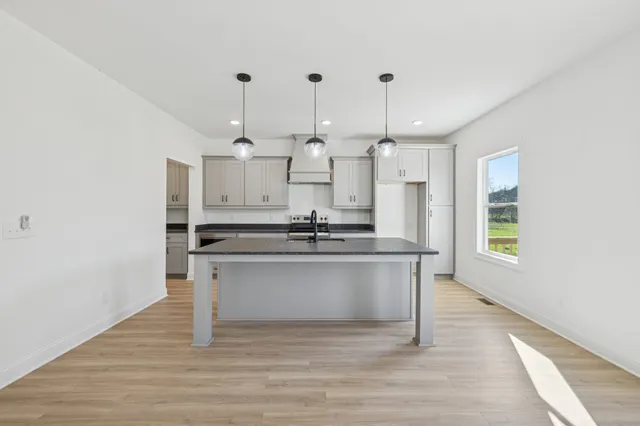 a large kitchen with granite countertop a large stove a sink and a wooden floor