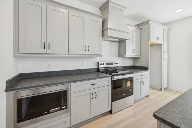 a kitchen with granite countertop white cabinets and stainless steel appliances