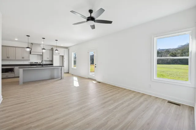 a view of a kitchen with a stove cabinets a ceiling fan and wooden floor