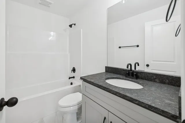 a bathroom with a granite countertop sink a toilet a mirror and shower