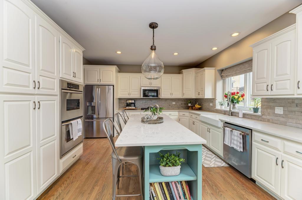 1061 Sean Circle Darien, IL 60561 - Photo 10 of 50 a large kitchen with stainless steel appliances kitchen island granite countertop a refrigerator a stove a sink a dining table and chairs with wooden floor