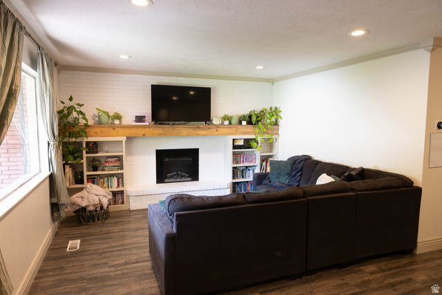 827 South 600 East Logan, UT 84321 - Photo 12 of 30 Living area featuring a white brick fireplace with a wood-beam mantel, recessed lighting, built-in shelving, and wood-finish flooring