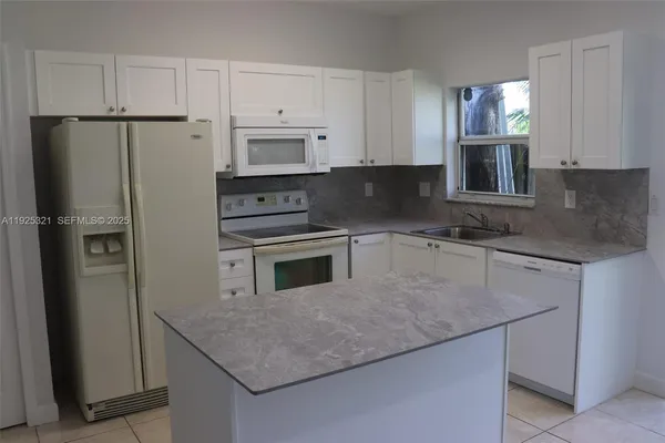 a kitchen with stainless steel appliances granite countertop a refrigerator a stove a sink and white cabinets