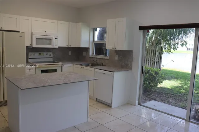 a kitchen with granite countertop a stove sink and microwave