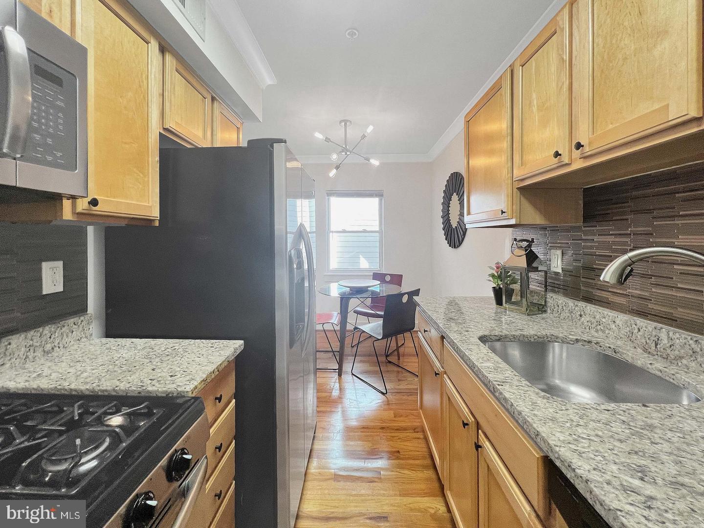 2615 4th Street Northeast, Unit 306 Washington, DC 20002 - Photo 6 of 13 a kitchen with stainless steel appliances granite countertop a sink a stove and a wooden cabinets