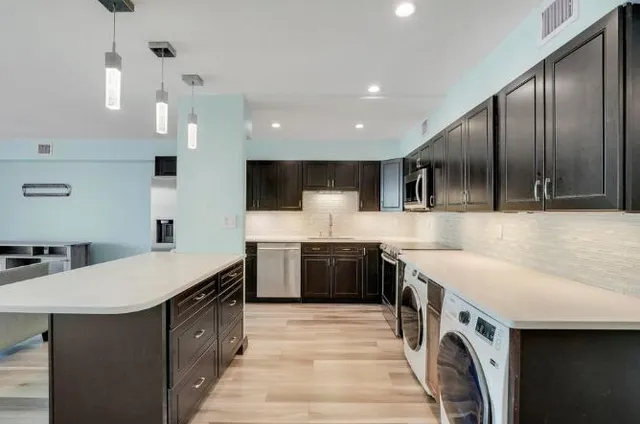 a large kitchen with stainless steel appliances granite countertop a sink a stove and a wooden floors