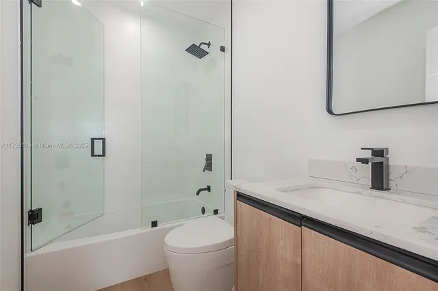 a bathroom with a granite countertop sink a toilet and shower