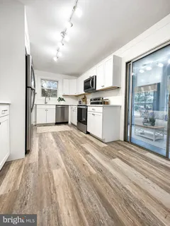 a large kitchen with kitchen island a sink dishwasher stove and white cabinets with wooden floor
