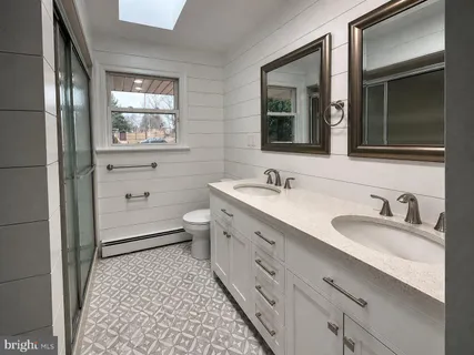 a bathroom with a double vanity sink toilet mirror and window