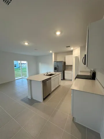 a large kitchen with kitchen island a sink a stove a counter space and cabinets