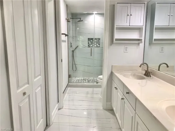 a bathroom with a double vanity sink a mirror and a shower