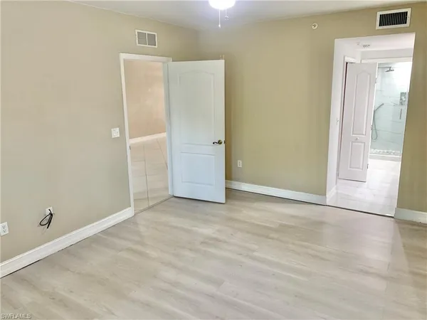 an empty room with wooden floor and mirror