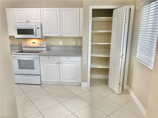a kitchen with white cabinets and appliances