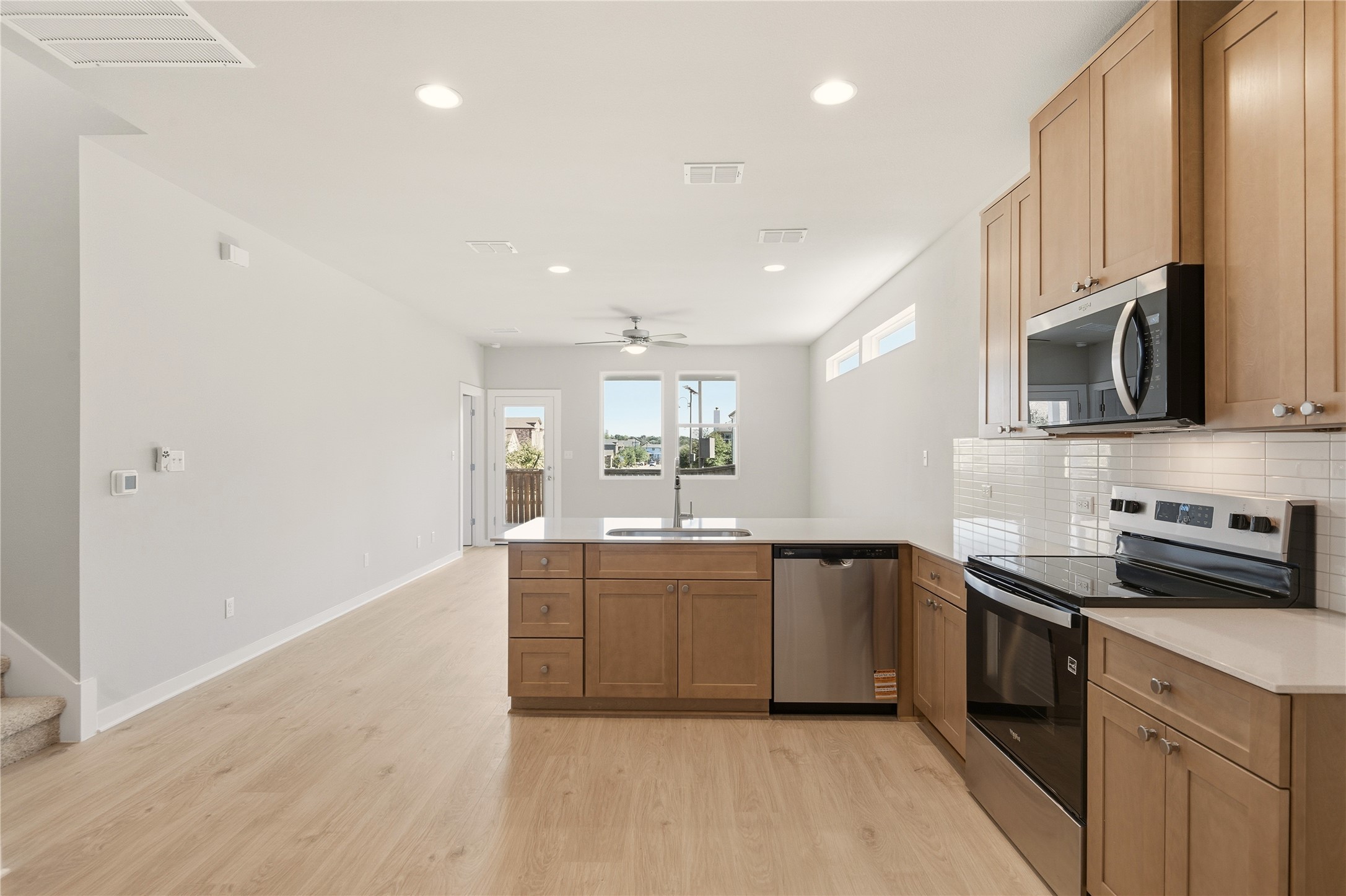 2201 Cento Walk Round Rock, TX 78664 - Photo 6 of 30 Kitchen featuring stainless steel appliances, a peninsula, backsplash, recessed lighting, and light wood-style flooring