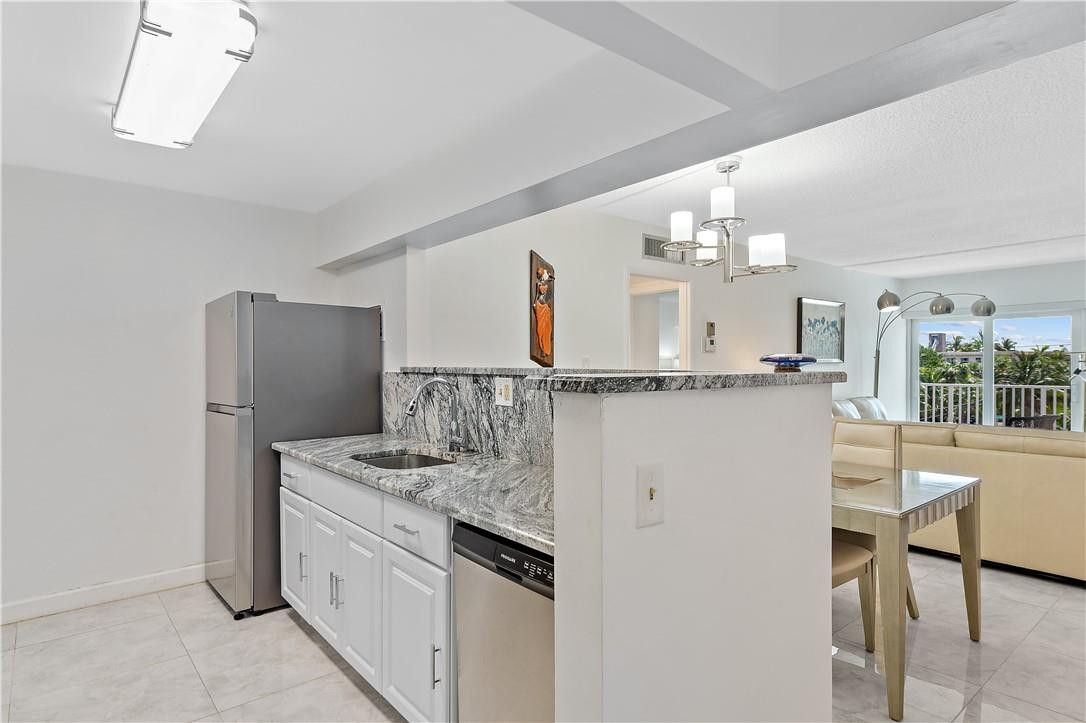 95 North Birch Road, Unit 405 Fort Lauderdale, FL 33304 - Photo 19 of 34 a kitchen with granite countertop a sink cabinets and stainless steel appliances