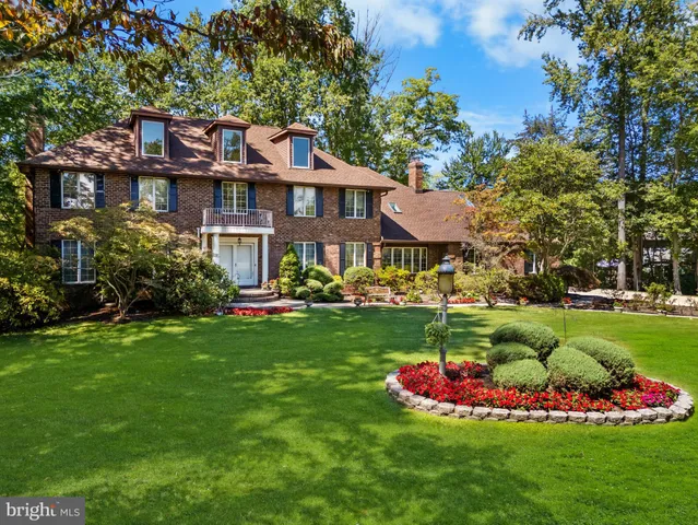 a front view of a house with a garden and trees