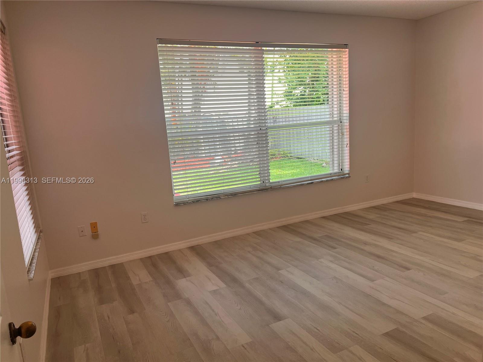 15761 Southwest 148th Terrace Miami, FL 33196 - Photo 13 of 17 a view of an empty room with wooden floor and a window