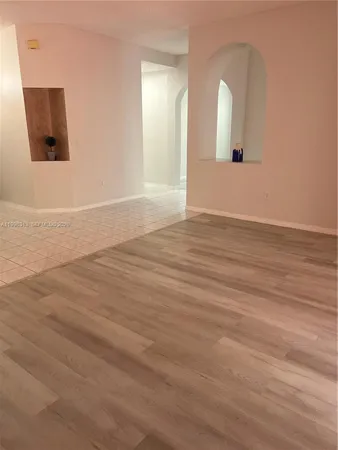 an empty room with wooden floor and mirror on side of a wooden floor