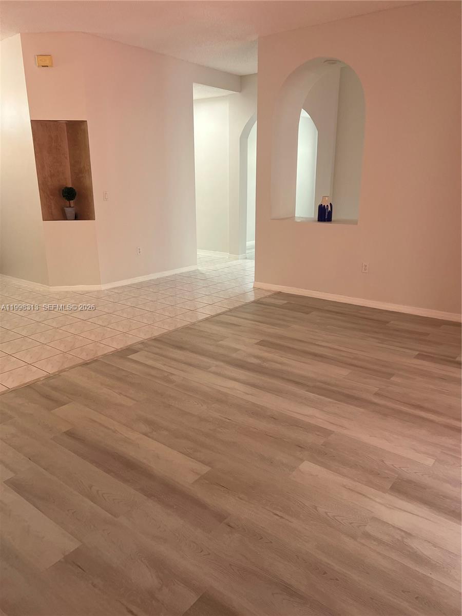 15761 Southwest 148th Terrace Miami, FL 33196 - Photo 5 of 17 an empty room with wooden floor and mirror on side of a wooden floor