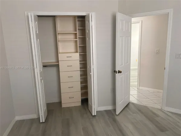 an empty room with wooden floor closet and windows