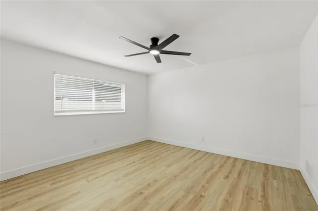 an empty room with a window and a fan