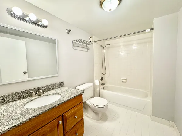a bathroom with a granite countertop sink a toilet a mirror and shower