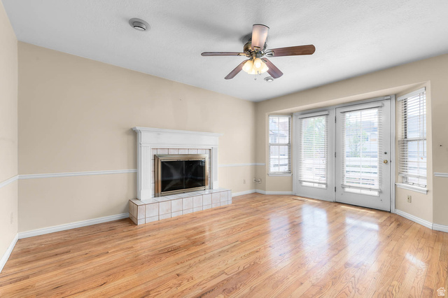 1822 East 9800th Street South Sandy, UT 84092 - Photo 28 of 38 Unfurnished living room with light wood finished floors, ceiling fan, and a fireplace