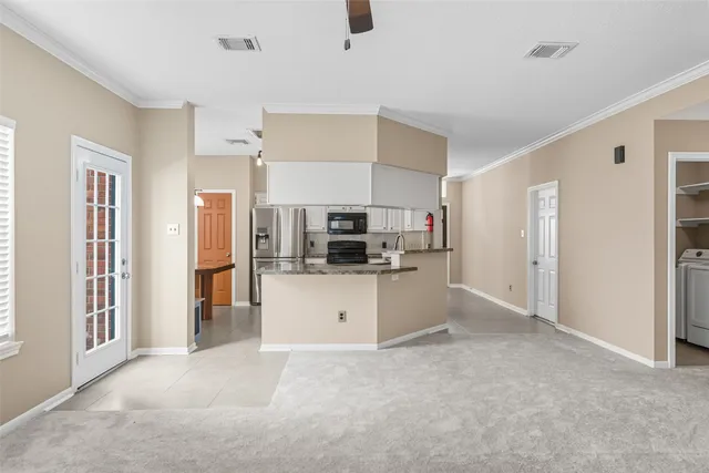 a kitchen with stainless steel appliances kitchen island a refrigerator sink and white cabinets