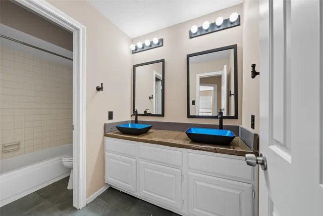 a bathroom with a granite countertop sink a mirror and a bathtub