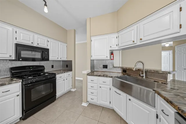 a kitchen with white cabinets and appliances