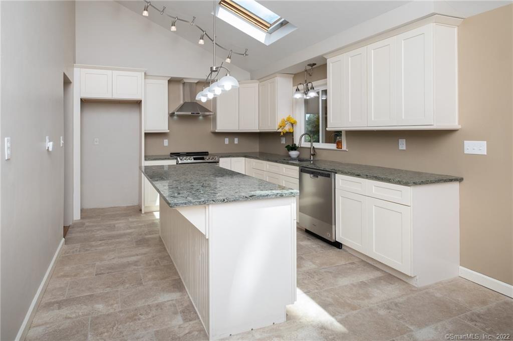a kitchen with kitchen island granite countertop a sink a counter top space and cabinets
