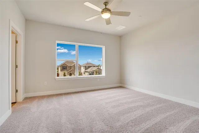 an empty room with windows and fan