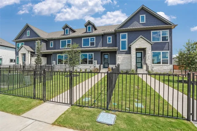 a view of a brick house with a small yard plants and large trees