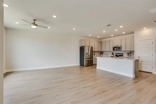 a view of kitchen with granite countertop refrigerator oven a white stove with cabinets and wooden floor