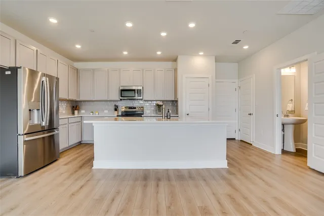 a large kitchen with stainless steel appliances a refrigerator and a stove top oven