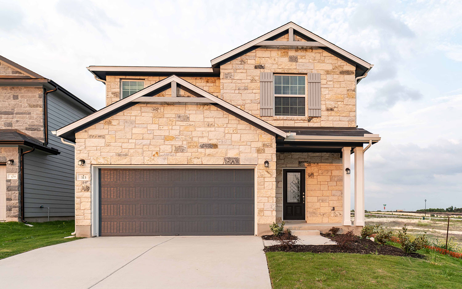 View of front facade with concrete driveway, an attached garage, and stone siding