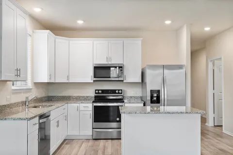 a kitchen with stainless steel appliances granite countertop a refrigerator sink and stove