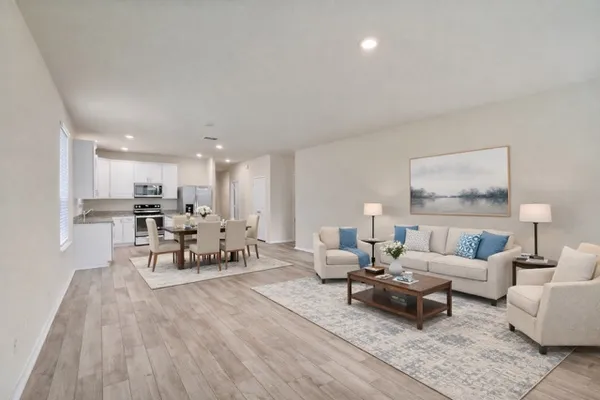 a living room with stainless steel appliances granite countertop furniture and a wooden floor